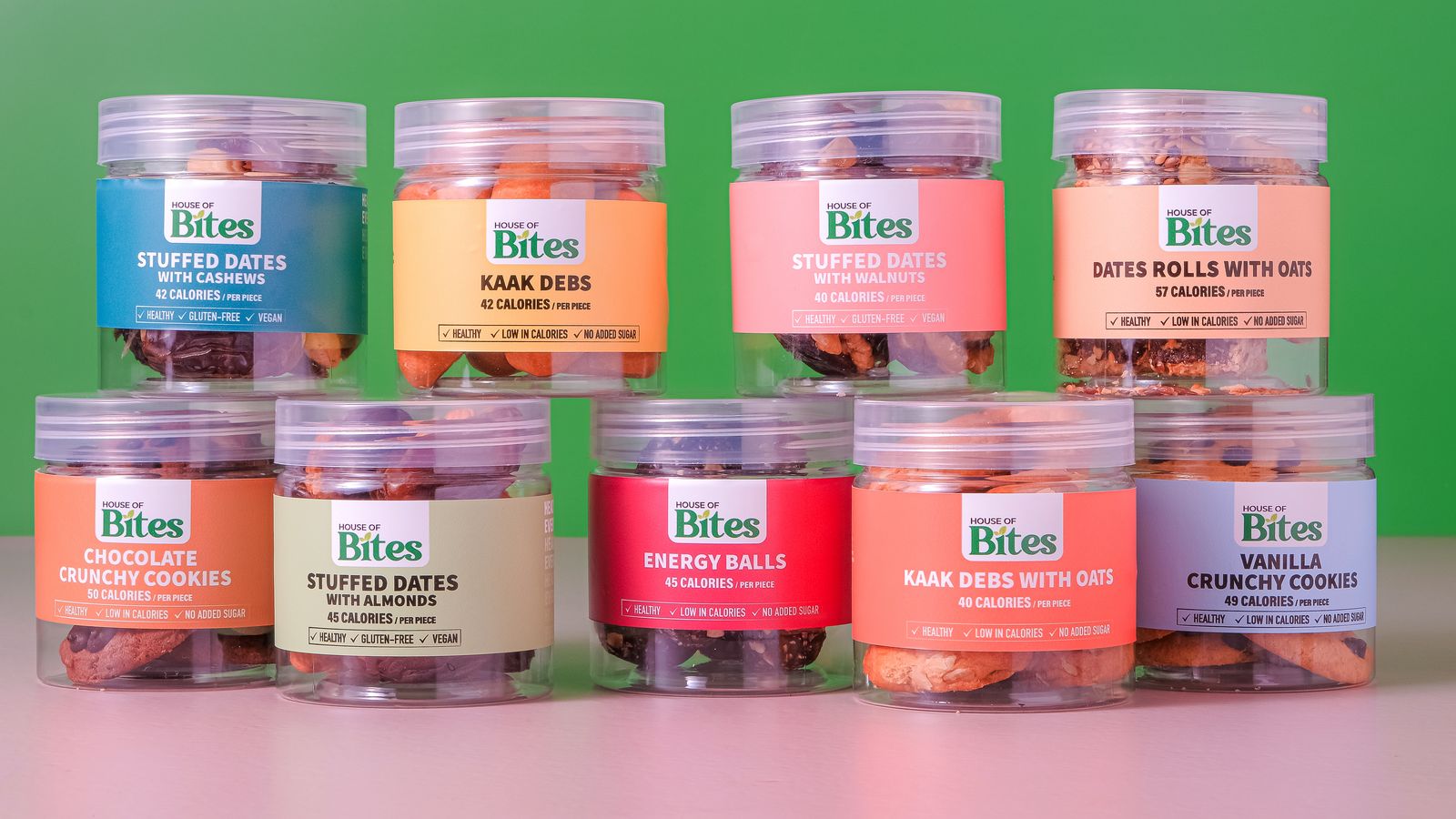 Nine House of Bites jars stacked on a green and pink background, each with its own colour label.