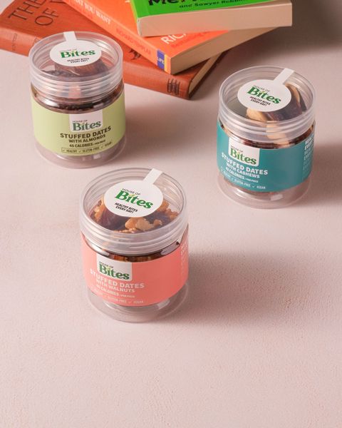 Three stuffed dates jars on a table beside a stack of books.